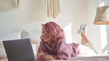 happy hipster gen z teen girl pink hair watching movie laptop bed 183911105