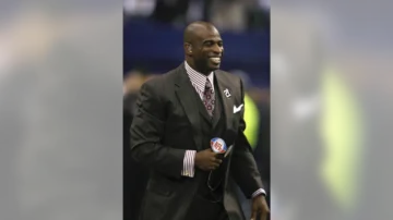 Man in suit holding NFL microphone, smiling. #tik4tat.com