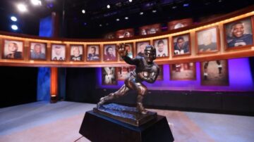 Heisman Trophy on display in gallery with portraits.